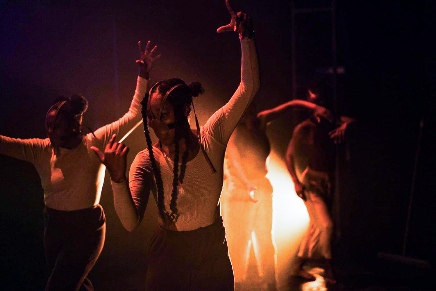 Performers in masks and vibrant lighting during a scene from the show UNMUTED